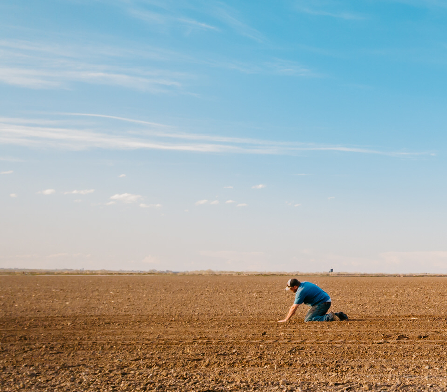 Farmer examining soil in a bare field